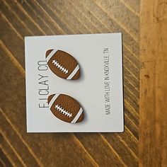 two brown leather footballs are sitting on a card