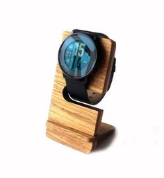 a wooden stand with a watch on it's face and the time displayed in blue