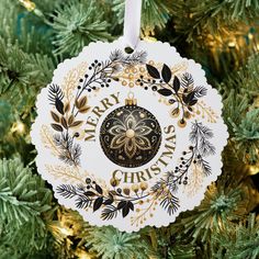 a merry christmas ornament hanging from a tree with gold and black decorations on it