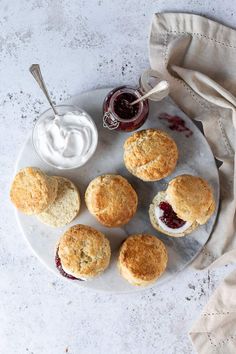 biscuits and jams on a plate next to a cup of cream cheesecake sauce