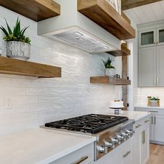 a kitchen with white counter tops and wooden shelves