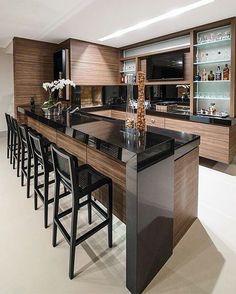 an image of a kitchen with black countertops and bar stools in the middle