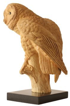 a carved owl sitting on top of a wooden stand