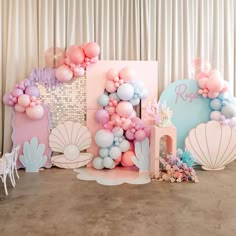 some balloons and other items are on the floor in front of a backdrop that says mermaid