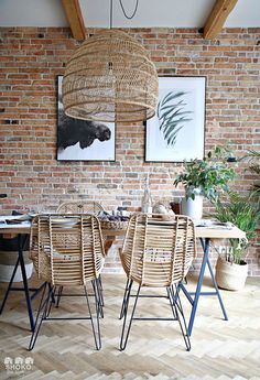 a dining room table and chairs in front of a brick wall with pictures on it