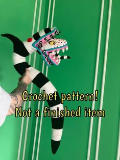 a person is holding two knitted dragon dolls in front of a green wall with the words crochet pattern not a finished item