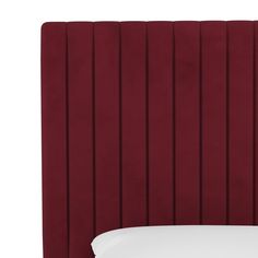 a red headboard with white sheets and pillows