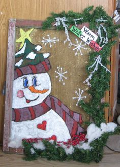 a snowman with a hat and scarf on is in front of a door decorated for christmas