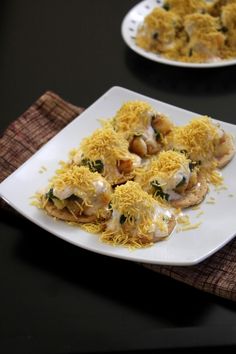 two white plates filled with food on top of a black tablecloth and napkins