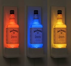 three bottles of jack daniels are lit up in different colors and shapes on the wall