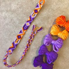 several different colored yarns are on the floor next to an orange, purple, and yellow string