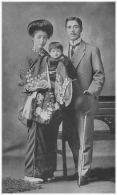 an old black and white photo of two people standing next to each other holding a doll