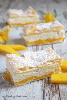 two pieces of dessert sitting on top of a wooden table next to bananas and powdered sugar