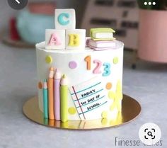 there is a cake that has letters and numbers on it with crayons next to it