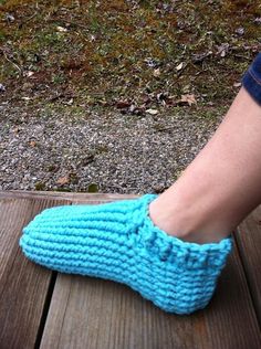 a woman's feet wearing blue slippers on top of a wooden bench outside