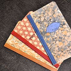 three notebooks are stacked on top of each other, one has a blue bird