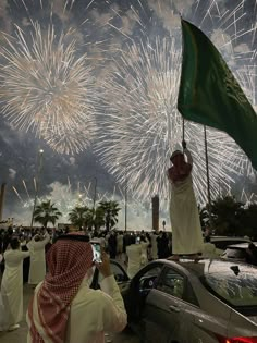 a group of people standing around a car with fireworks in the background