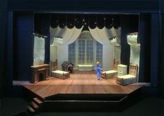 the stage is set for a play with furniture and curtains in front of a window