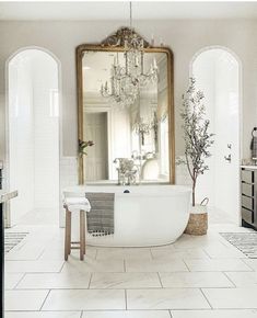 a bathroom with a tub, mirror and chandelier hanging from it's ceiling