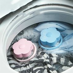 two cups are sitting in the top of a washing machine filled with water and cloths