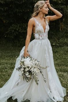 a woman in a white wedding dress holding a bouquet and looking off into the distance