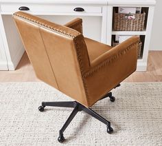 a brown leather office chair sitting on top of a white rug in front of a desk