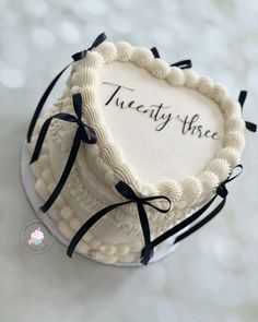 there is a heart shaped cake with the words twenty three on it and black ribbons