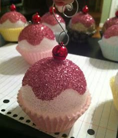 some cupcakes with pink and white frosting are on a table next to other cupcakes