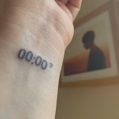 a person with a small tattoo on their wrist that reads, 0009 '