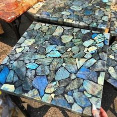 two tables made out of rocks with one being painted blue