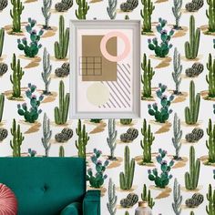 a green chair sitting in front of a wall with cactus print on it and a framed photo