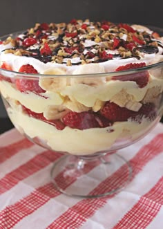 a dessert dish with strawberries, bananas and other toppings in a glass bowl