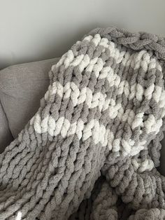 a gray and white blanket sitting on top of a couch