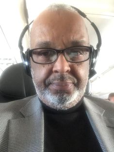 an older man wearing headphones and a suit