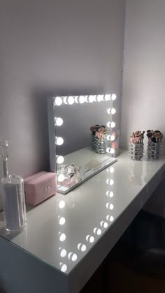 a vanity with a lighted mirror and some bottles on the counter top next to it