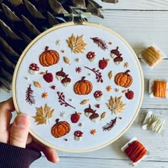 someone is holding up a cross stitch pattern with autumn leaves and acorns on it