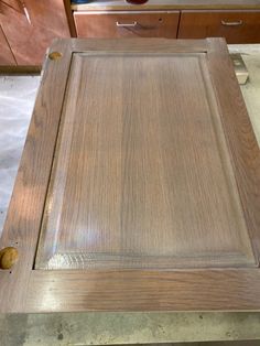 an unfinished cabinet door is shown in the process of being sanded and painted with wood glue