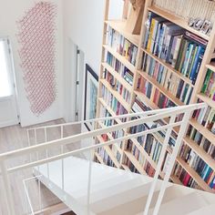 there is a stair case full of books in this room with the stairs up to the second floor