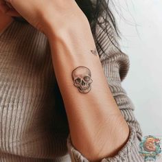 a woman's arm with a skull tattoo on the left side of her arm