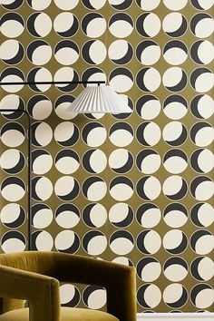 a chair and lamp in front of a wall with black and white circles on it