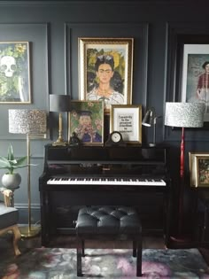 a piano in a living room with pictures on the wall behind it and a lamp next to it