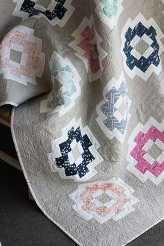 a quilted blanket with many different designs on the top and bottom, along with two pillows