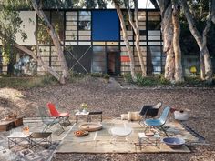 an outdoor table with chairs and plates on it in the middle of a yard surrounded by trees