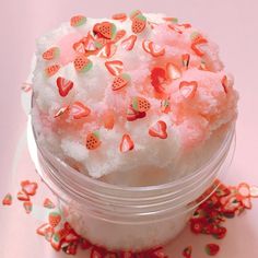 a small jar filled with lots of pink and orange sprinkles on top of a table