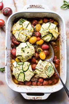 a casserole dish filled with tomatoes, zucchini and cucumbers