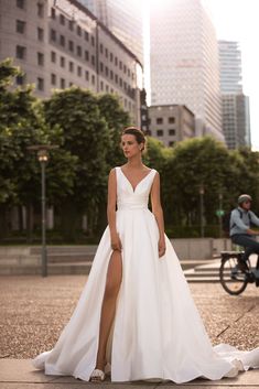 a woman in a white wedding dress standing on the street