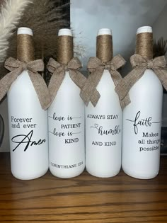 three white wine bottles with burlocks tied to them on top of a wooden table