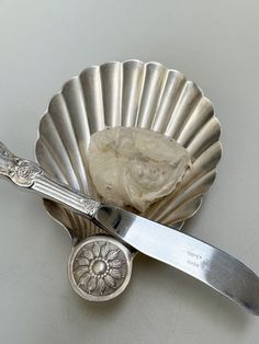 a spoon and knife sitting on top of a silver plate next to a shell shaped container