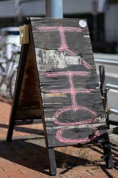 a chalk drawing sign sitting on the side of a road next to a bike rack