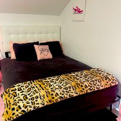 a bedroom with a leopard print bed spread and two pillows on top of the bed